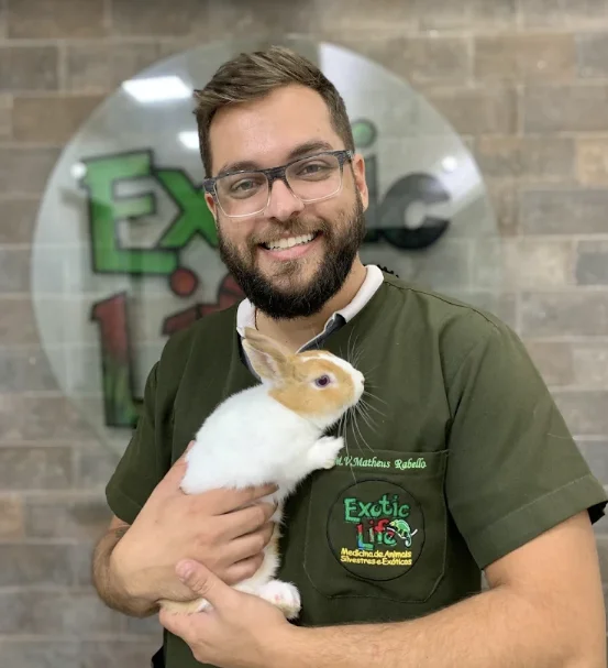 Integrante da equipe Exotic Life segurando um coelho branco e marrom